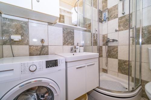 a bathroom with a washing machine and a sink at Spacious apartment 50 m from the beach in Postira