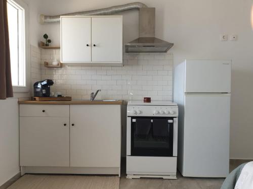 una cucina con armadietti bianchi, piano cottura e frigorifero di ēnNĒ Studios for Views & Tranquility a Ftelia