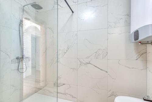 a bathroom with a shower with white marble walls at Holiday House Lena in Baderna
