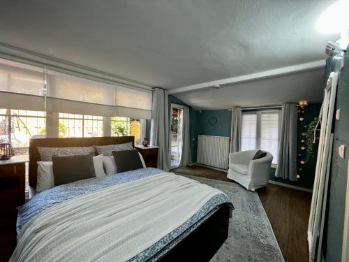 a bedroom with a bed and a chair and windows at Ferienwohnung Terrassenblick in Zülpich
