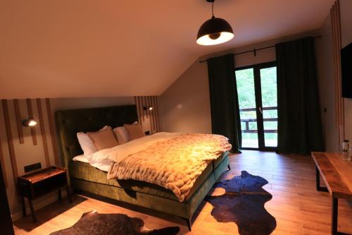 ein Schlafzimmer mit einem großen Bett und Holzboden in der Unterkunft Wild Hunts Lodge Retezat in Rausor