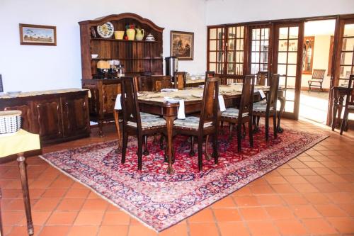 a dining room with a table and chairs on a rug at Villa Jana Guesthouse in Pretoria