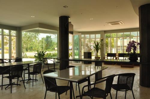 a dining room with tables and chairs and windows at Khaoyai Terrazzo in Mu Si