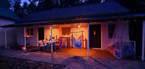 a house with a deck with a table and chairs at Dom Pracy Twórczej Macondo in Miedzno