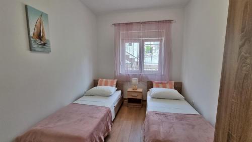 two twin beds in a room with a window at Apartment Gogo Duce in Duće