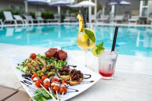 a plate of food and a drink next to a pool at Hotel Malavoglia in Acitrezza