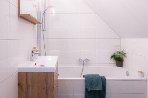 een witte badkamer met een wastafel en een bad bij Luxe Vakantiehuis Koekoek Veluwe in Nunspeet
