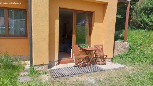 une table et des chaises assises à l'extérieur d'une maison dans l'établissement Apartmán Tatran Donovaly, à Donovaly