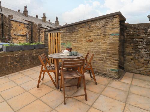 a table and chairs on a patio with a brick wall at 2 James Street in Keighley