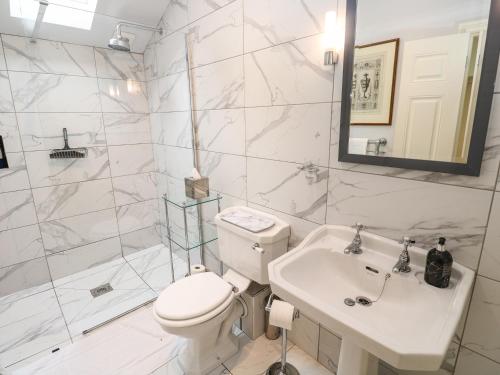 a white bathroom with a toilet and a sink at The Coach House at Pendower House in Fowey