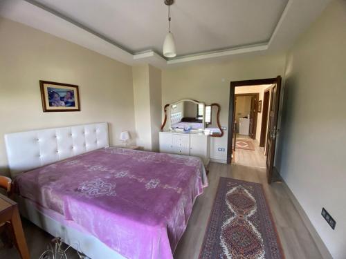 1 dormitorio con cama morada y espejo en Arpacılı Köyünde Müstakil Ev, en Akcaabat