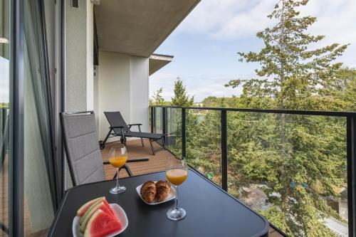 a table with two glasses of wine and fruit on a balcony at Wellness Resort & SPA Dziwnów Apartments with Parking by Noclegi Renters in Dziwnów