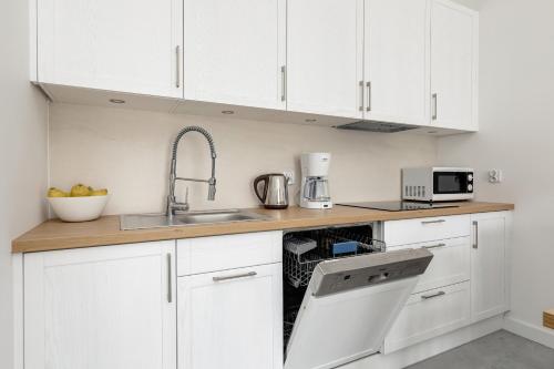 a white kitchen with a sink and a dishwasher at Wellness Resort & SPA Dziwnów Apartments with Parking by Noclegi Renters in Dziwnów