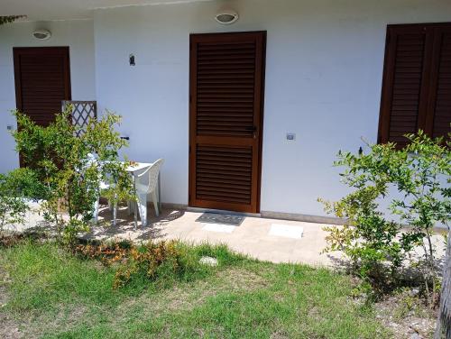a white house with a wooden door and a chair at Barrumbas in Santa Lucia