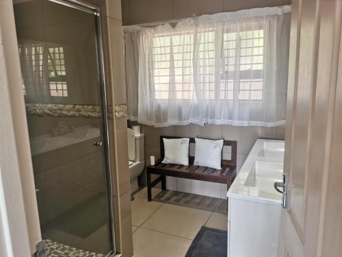 uma casa de banho com um chuveiro, um lavatório e um WC. em Cycadales Villa em Sabie