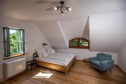 a bedroom with a bed and a blue chair at Oszter Udvarház in Kékkút