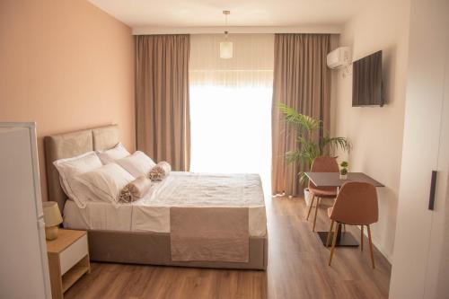 a bedroom with a bed and a table and a window at Wave Beachfront Apartments in Durrës