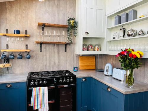 a kitchen with blue cabinets and a stove top oven at Nightingale Cottage in Llantwit Major