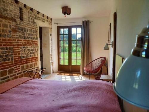 une chambre avec un lit et un mur de briques dans l'établissement La Maison Silleron, à Angiens