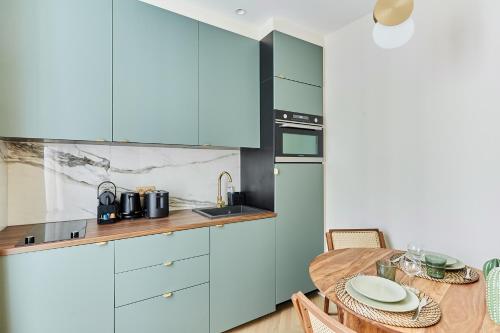 une cuisine avec des placards bleus et une table en bois avec une salle à manger dans l'établissement Apartment Champs Elysée bu Studio prestige, à Paris