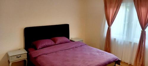 Un dormitorio con una cama con sábanas moradas y una ventana en Carmen apartman en Brčko