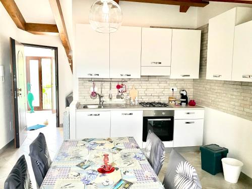 a kitchen with white cabinets and a table with chairs at Villa Marco Aurelio in Cisano sul Neva