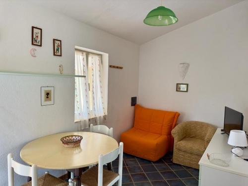 a living room with a table and an orange chair at Tramonto, Rena Majore in Rena Majore