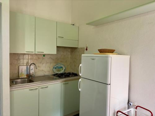 a kitchen with white cabinets and a white refrigerator at Tramonto, Rena Majore in Rena Majore