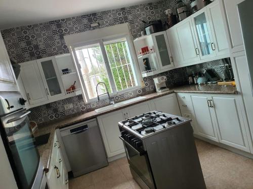 uma cozinha com armários brancos e um forno com placa de fogão em Finca amor y sueño isa em Rafal