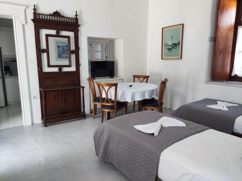 a hotel room with two beds and a table and a television at Achilleas Apartment in Hydra