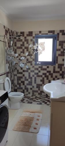 een badkamer met een wastafel, een toilet en een raam bij Villa Mirella in Tselendáta