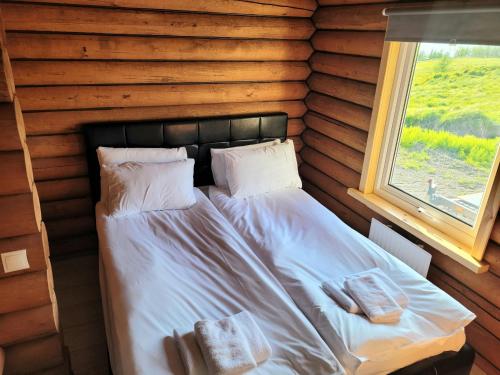a bed in a log cabin with a window at Akureyri Loghouse in Akureyri