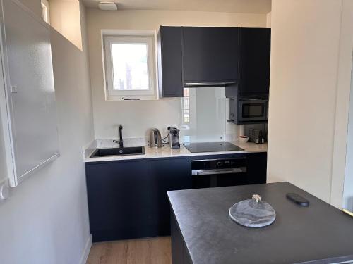 une cuisine avec des armoires noires et un comptoir dans l'établissement Appartement de charme entier, ambiance maison avec vue, à Trouville-sur-Mer