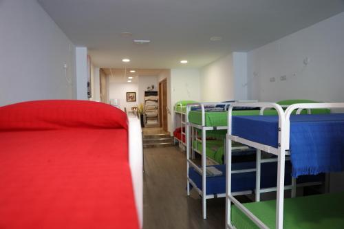 um quarto com 3 beliches e uma cama vermelha em ALBERGUE EL CAMINANTE em Portomarín