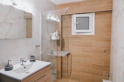a bathroom with a sink and a shower with a mirror at C Apartments in Melissátika
