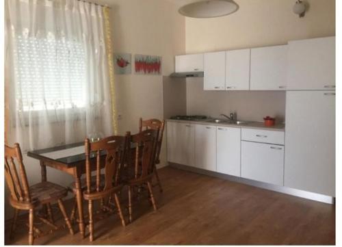 kuchnia ze stołem, krzesłami i białymi szafkami w obiekcie Apartment Olives w mieście Zadar