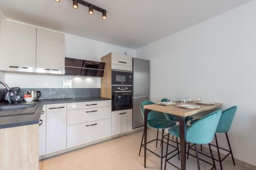 une cuisine avec des armoires blanches et une table avec des chaises dans l'établissement Dans le Pré by Plaza, à Chessy