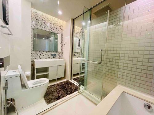 a bathroom with a toilet and a glass shower at Luxurious in Prime Area Bangkok (PickupService) in Bangkok