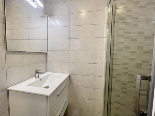 ein weißes Bad mit einem Waschbecken und einer Dusche in der Unterkunft ANTENA CITY APARTMENT in Benidorm