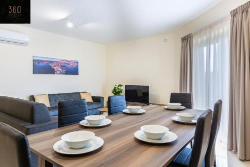 - une salle à manger avec une table et des chaises en bois dans l'établissement Serene 2BR Apartment with Picturesque Views by 360 Estates, à Marsaxlokk