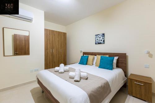 a bedroom with a large bed with blue and white pillows at Serene 2BR Apartment with Picturesque Views by 360 Estates in Marsaxlokk