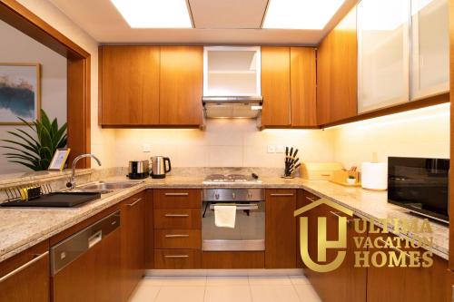 a kitchen with wooden cabinets and stainless steel appliances at Stylish 1BR-Next to Dubai Mall in Standpoint B in Dubai