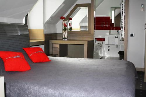 a bedroom with a large bed with red pillows at Garni Hotel Leopold I in Novi Sad