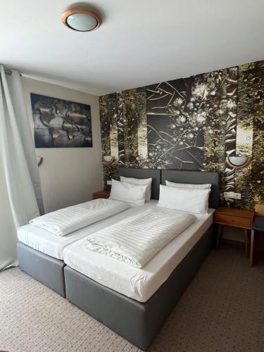Hotel Aggertal في غومرسباخ: غرفة نوم بسرير كبير عليها لوحة على الحائط