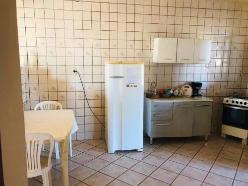 a white refrigerator in a kitchen with a table at Jacaraipe ES -Lar de Praia casa temporada in Jacaraípe