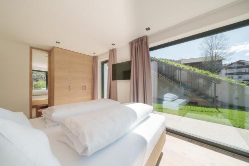 a bedroom with two beds and a large window at Villa Rames in Ortisei