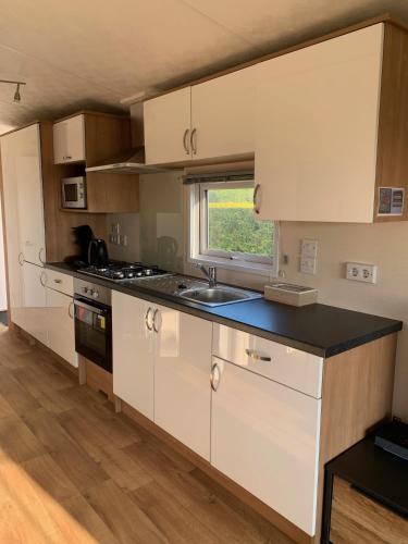 a kitchen with white cabinets and a sink and a window at Chalet Rivendell in Menaldum