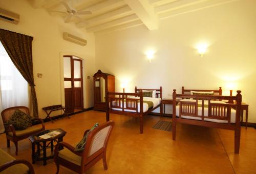 a room with three beds and chairs in a room at Palais De Mahe - A CGH Earth Experience in Puducherry