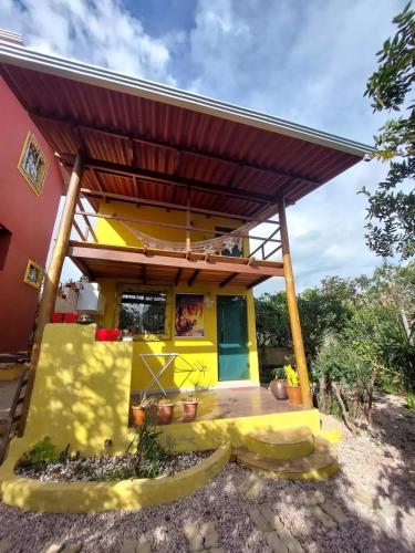 a small yellow house with a roof at Chalé tribal in Alto Paraíso de Goiás