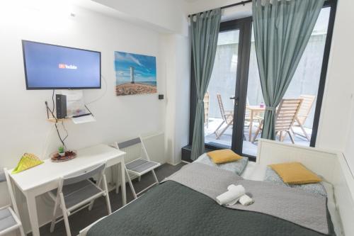 een slaapkamer met een bed, een bureau en een televisie bij Peaceful Basement Apartment with Terrace & free GYM in Boedapest